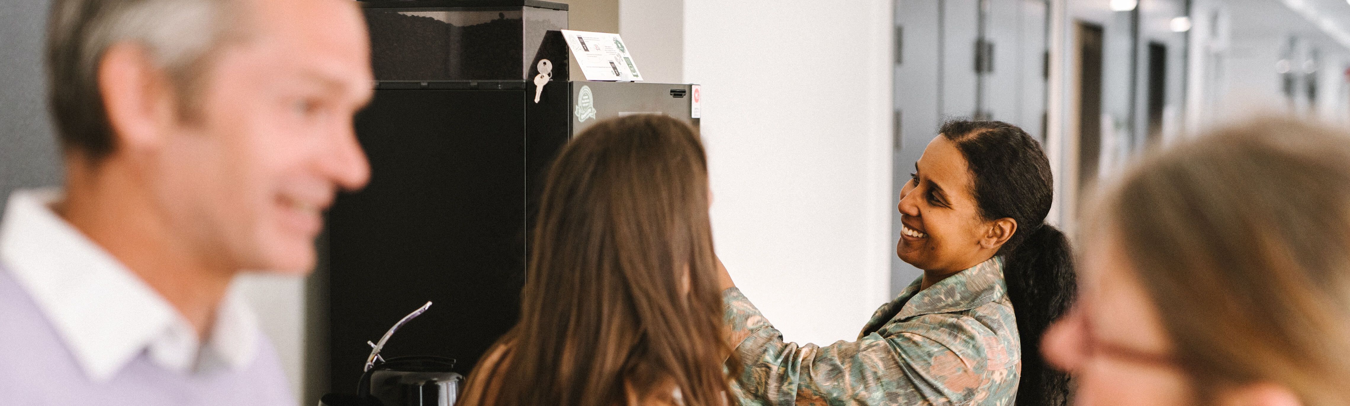 Fyra kollegor som samtalar och tar kaffe i ett personalrum på konto